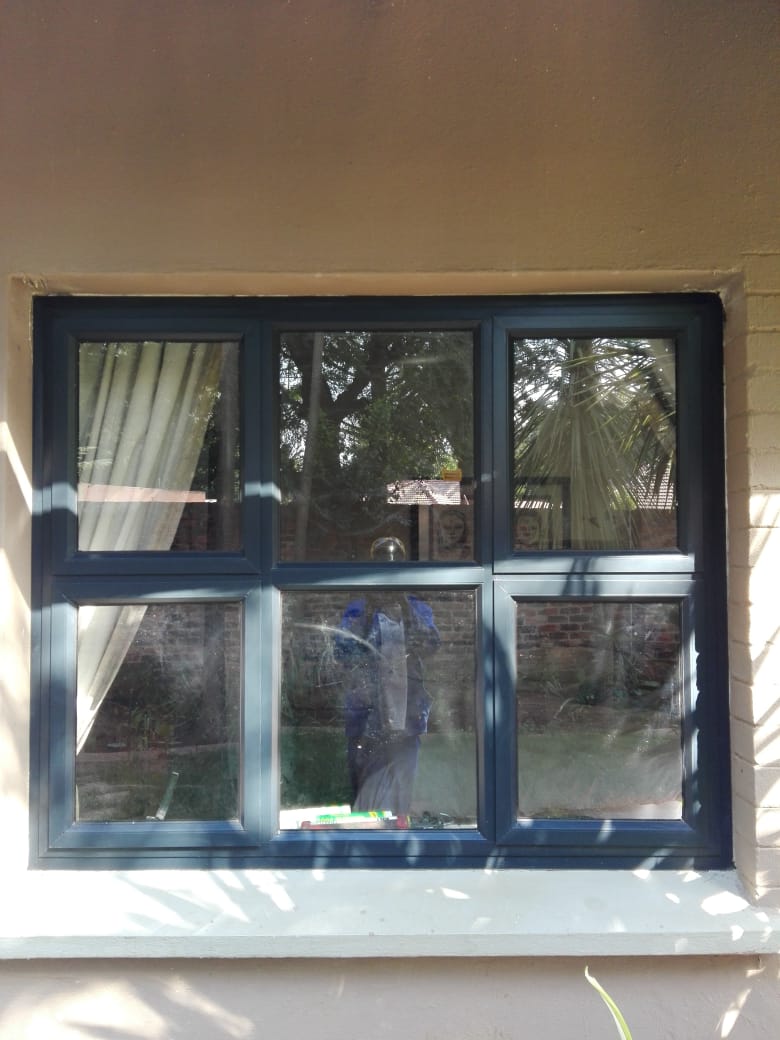 Dark aluminium six-pane window installed in a plastered wall