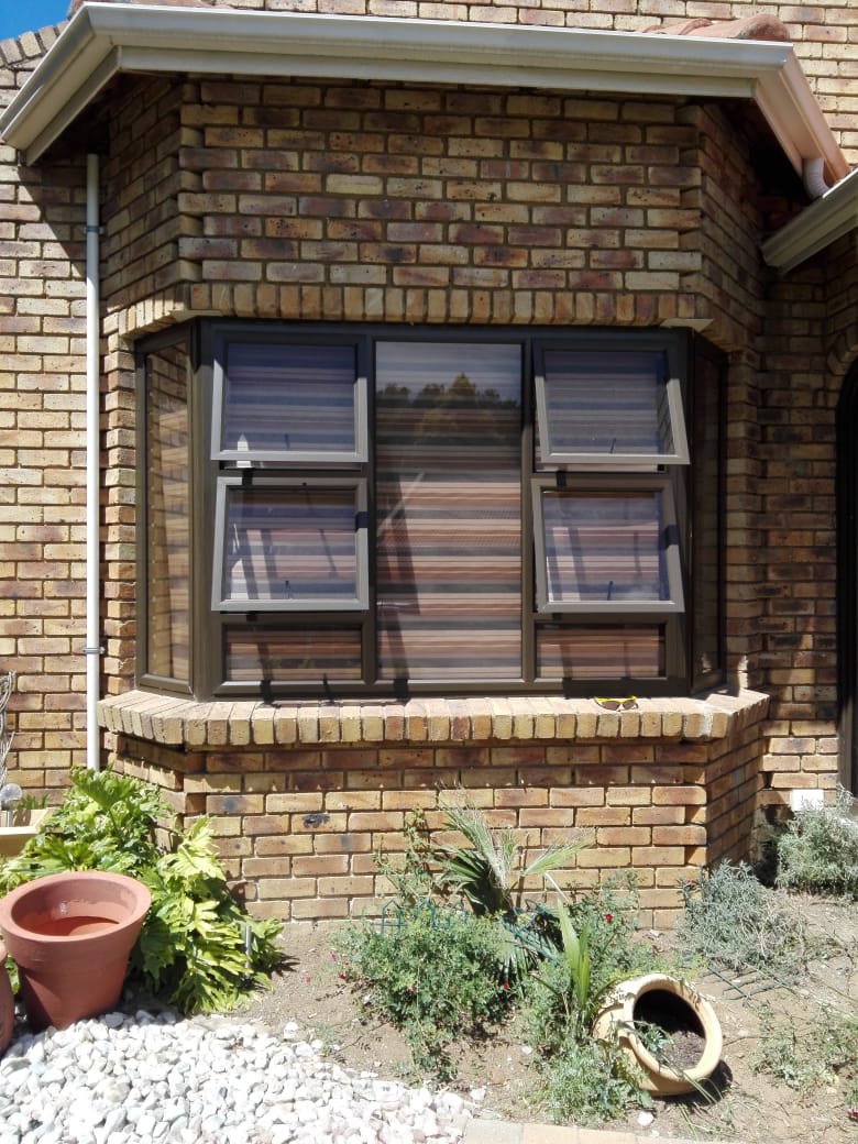 Aluminium bow window with openable top panes set in face brick bay
