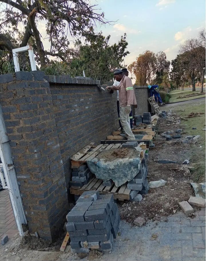 Bricklayers constructing a long boundary wall