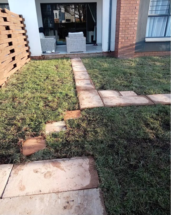 Paved walkway connecting a lawn to a residential patio