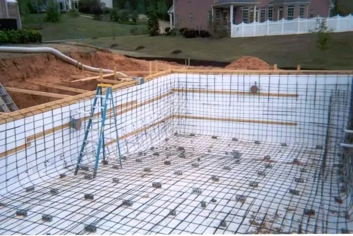 Swimming pool shell under construction with reinforcement mesh over waterproofed walls